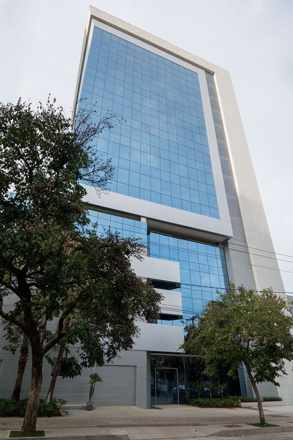 Sede da Direcional, torre comercial de vidro azul cercada por árvores
